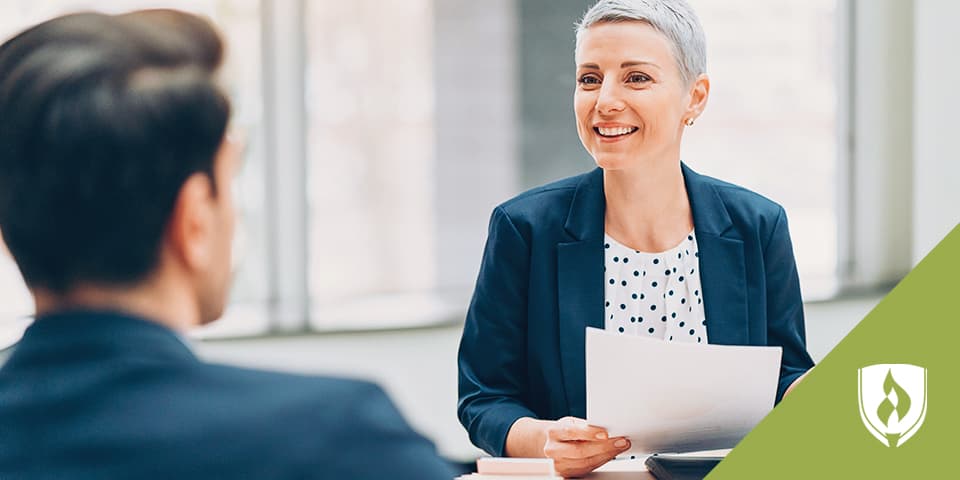 Image depicts professionally-dressed man and woman discussing a work matter.