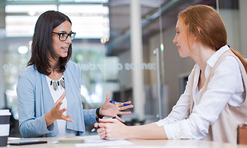 two female students talking at table